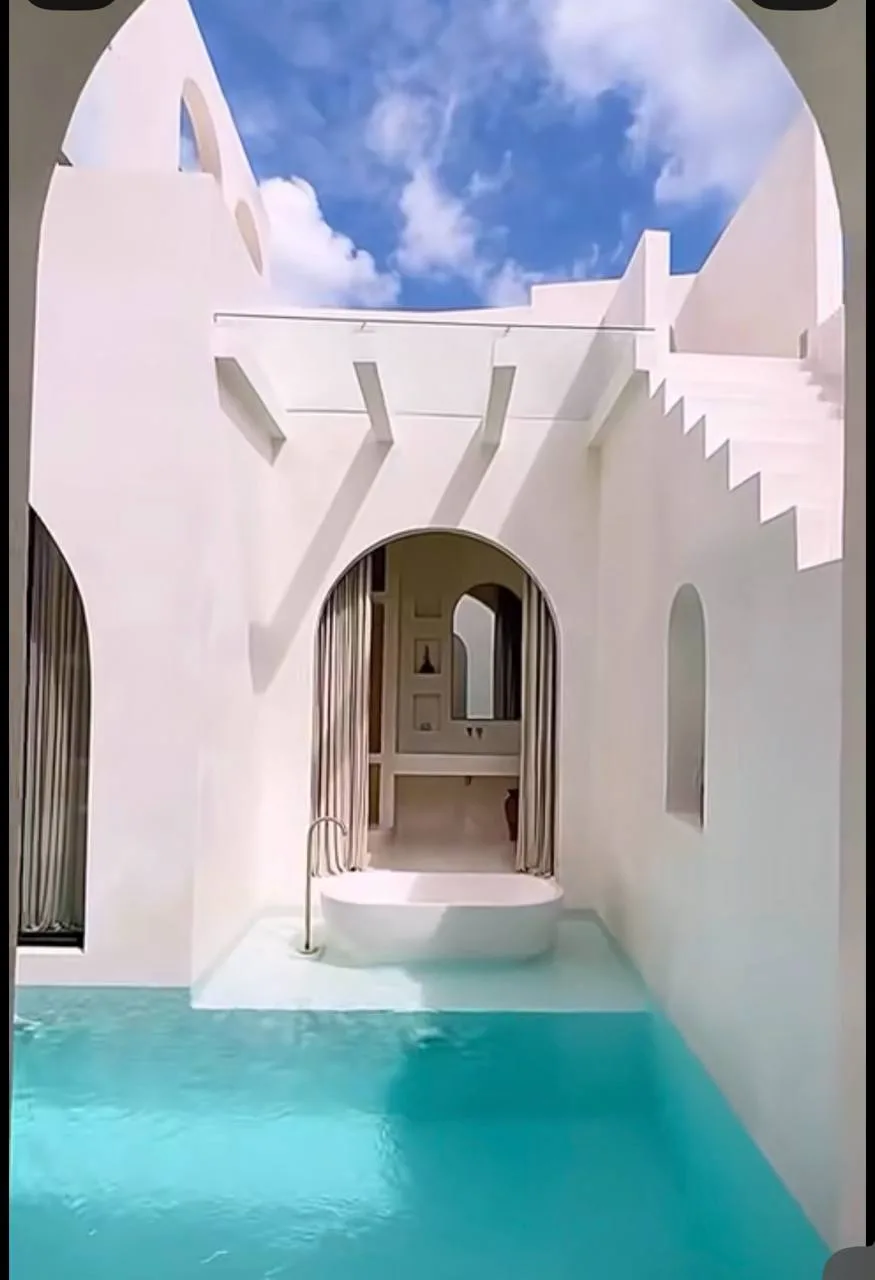 Raw concrete pool shell with scaffolding and arched niches, then finished white plaster courtyard with turquoise water.