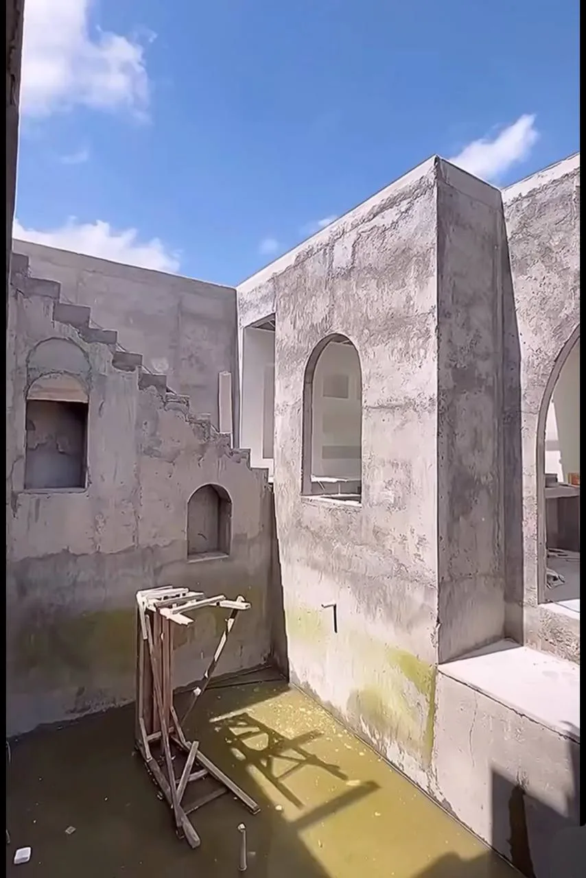 White Courtyard Pool & Arched Minimalist Shell — before — Grey plaster courtyard with standing water and arched niches, then finished white walls, stairs, niches, and pool.