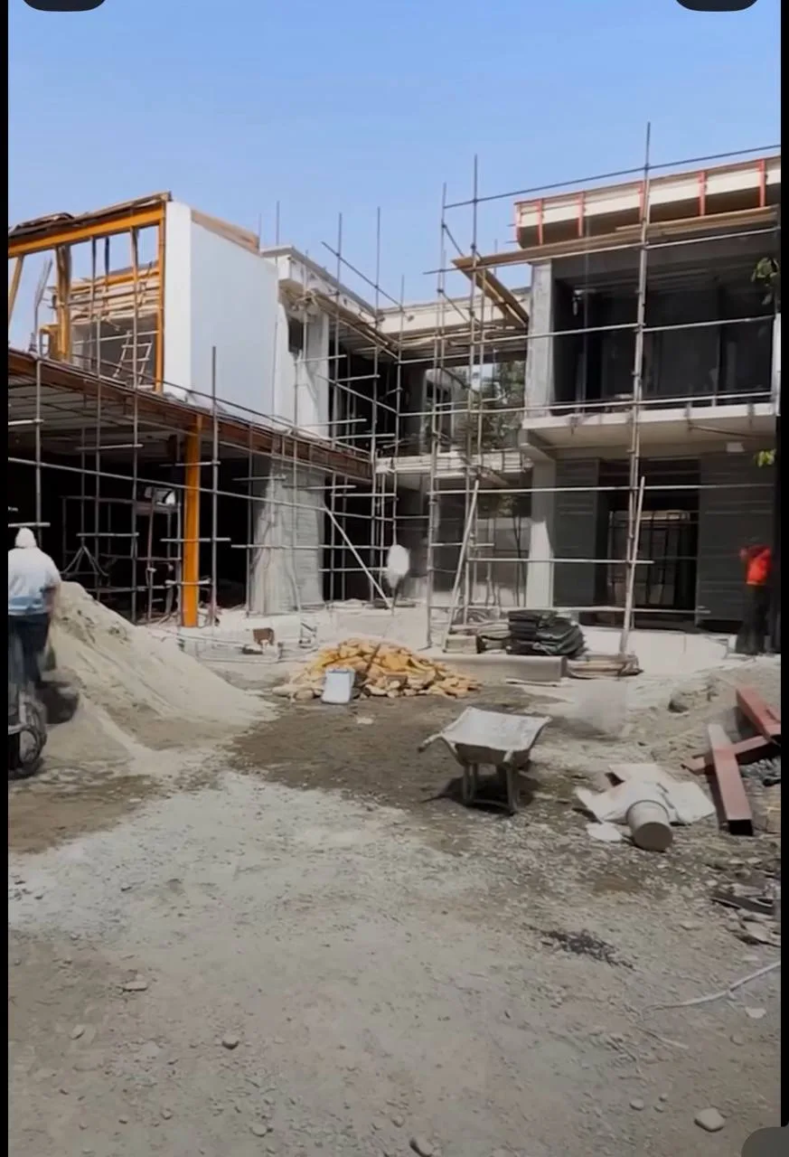 Modern Glass Villa: Pool Courtyard & Landscape — before — Same modern courtyard during hardscape work, then completed pool edge landscaping and glass facade.
