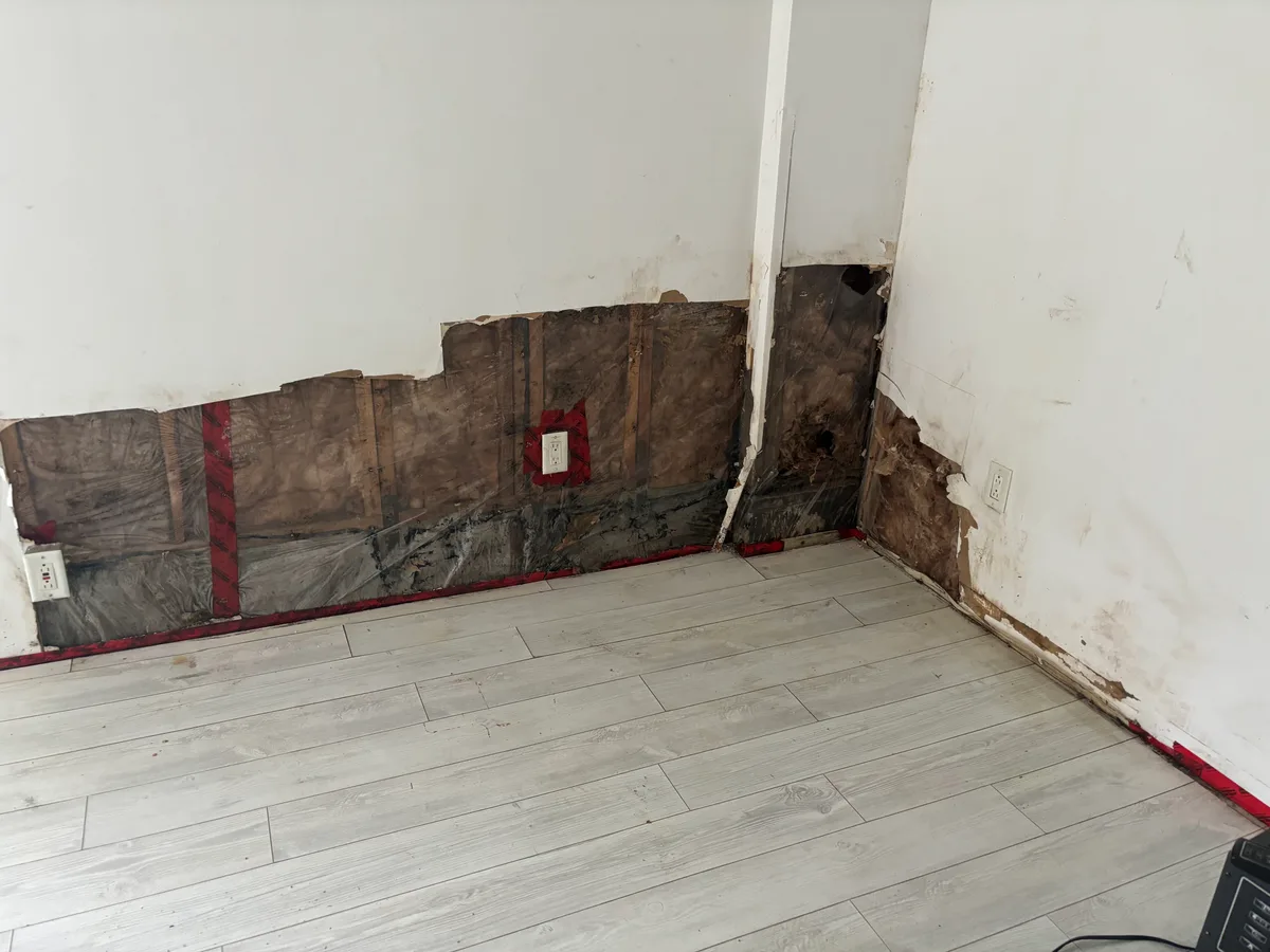 Metro Vancouver Interior: Flooring, Kitchen & Bath — before — Lower drywall cut back exposing insulation on the same light plank floor, then finished bedroom with closet and blinds.