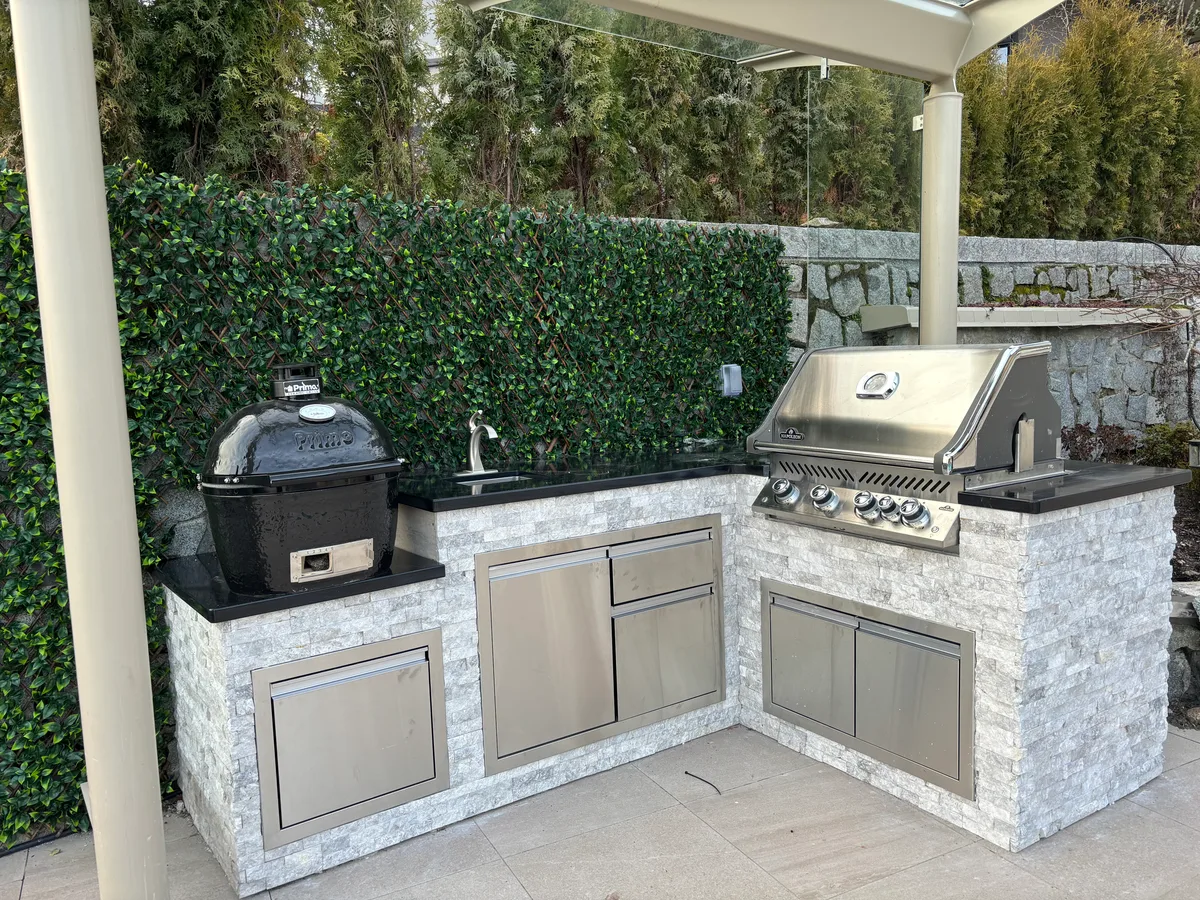 Outdoor kitchen island mid-install with protective film on cabinets, then finished counters, sink, and unwrapped stainless fronts.
