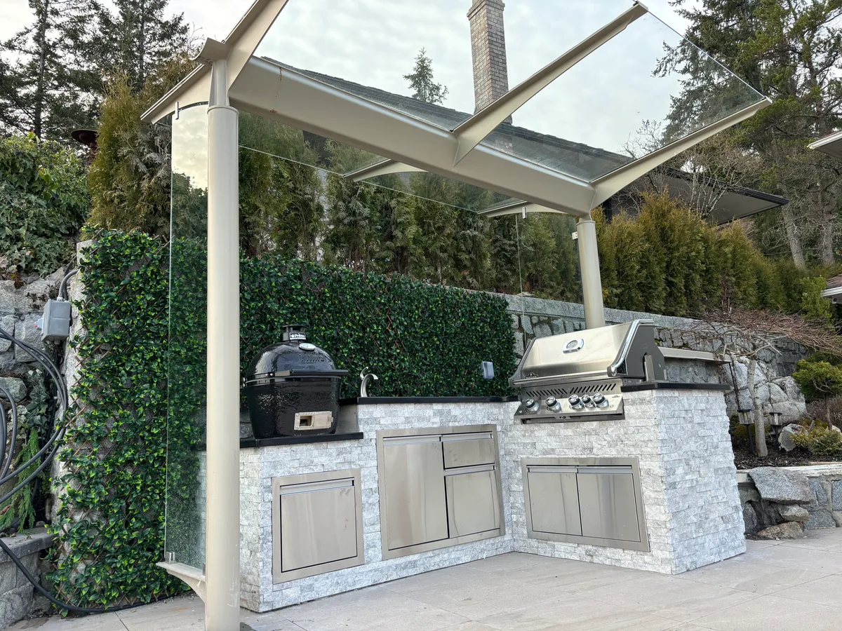 Timber framing for the overhead cover, then completed glass-roof canopy over the outdoor kitchen.